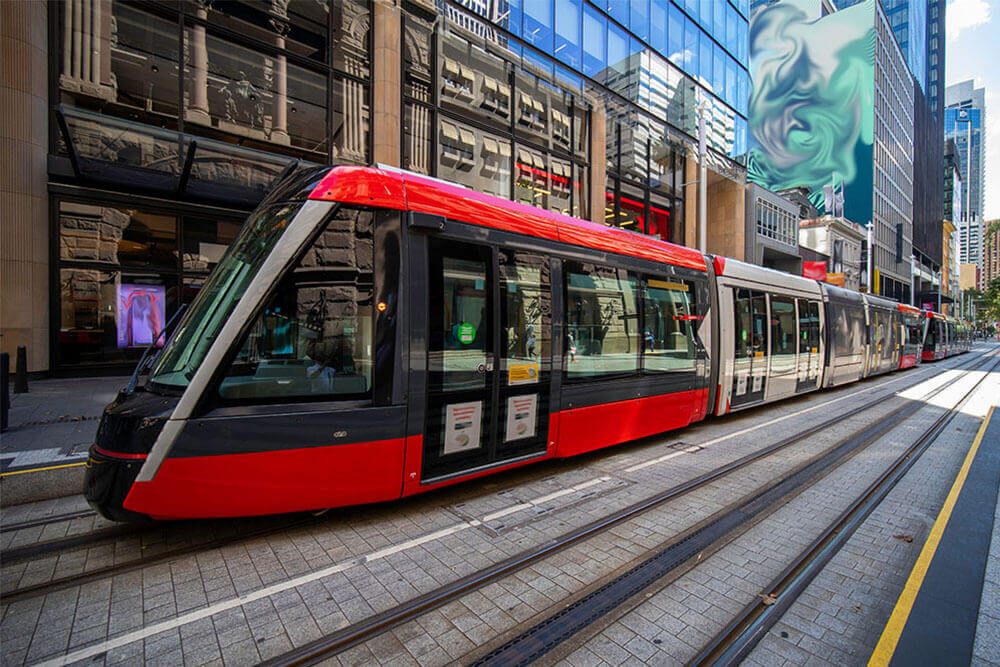 a red tram moving through the middle of a city