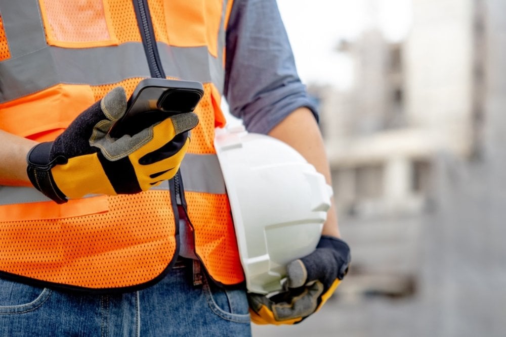 Tradie holding phone and helmet