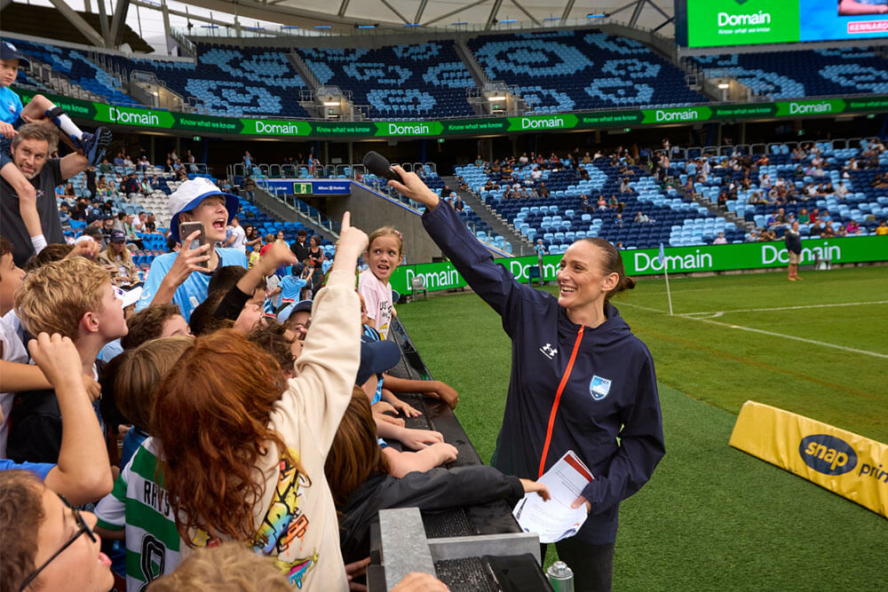 Sydney FC fans reaching towards fans in the stands