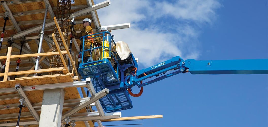 A close up of the basket of a large boom lift and people in it working on a construction site