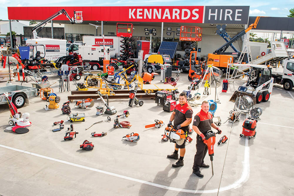 A birds eye view of a Kennards Hire branch - a large range of equipment spread out with two Kennards Hire team members standing in front