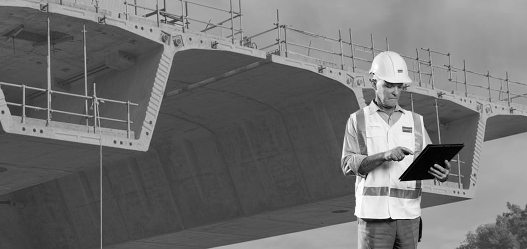 one person using a tablet with a bridge under construction in the background