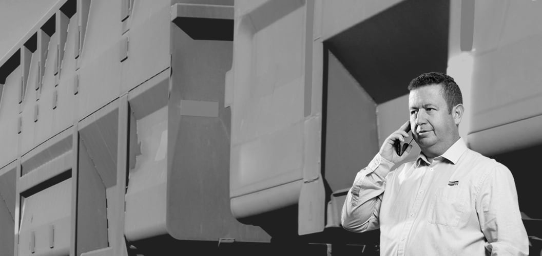 a person on the phone with industrial train carriages in the background