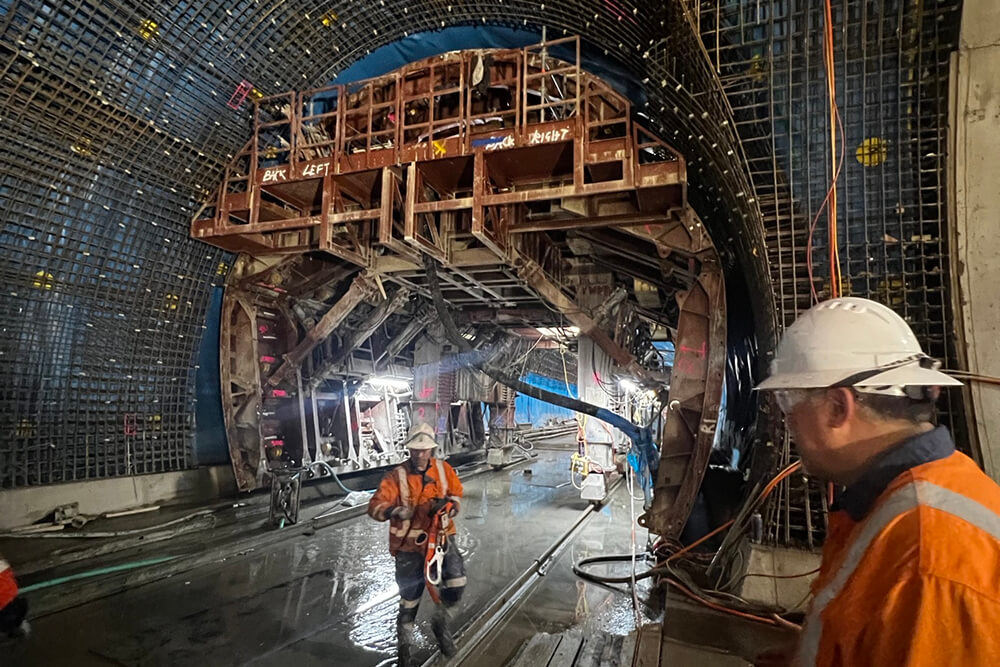 Rail workers walking around an underground rail tunnel 
