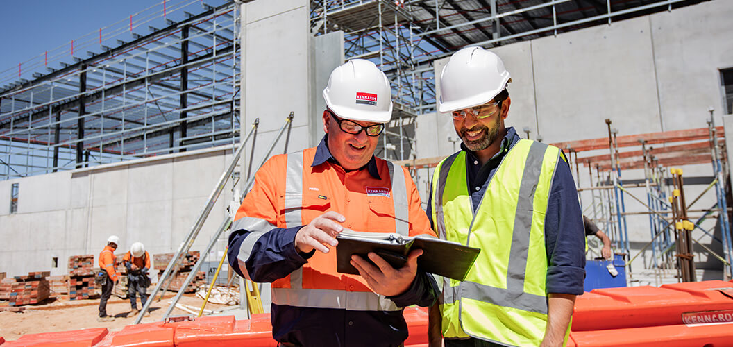 A Kennards Hire team member speaking to a project manager on a large construction site