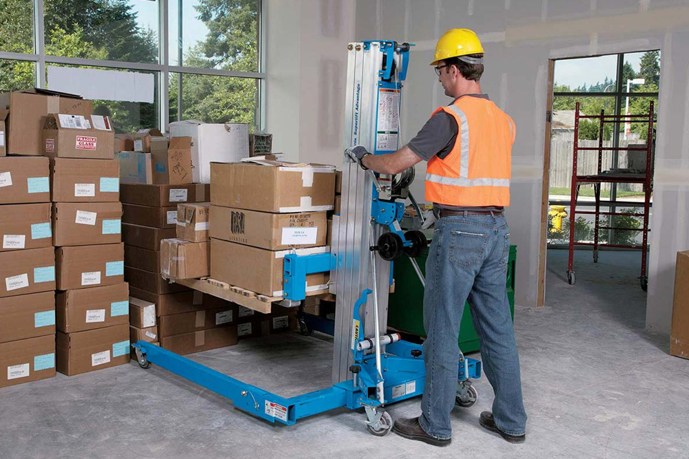 Person moving boxes with a material hoist indoors
