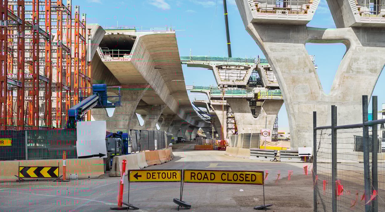 Detour Road Closed sign in front of a large construction site