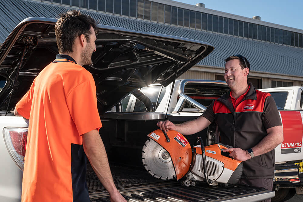 Kennards Hire team member loading a demolition saw into a trade customers ute
